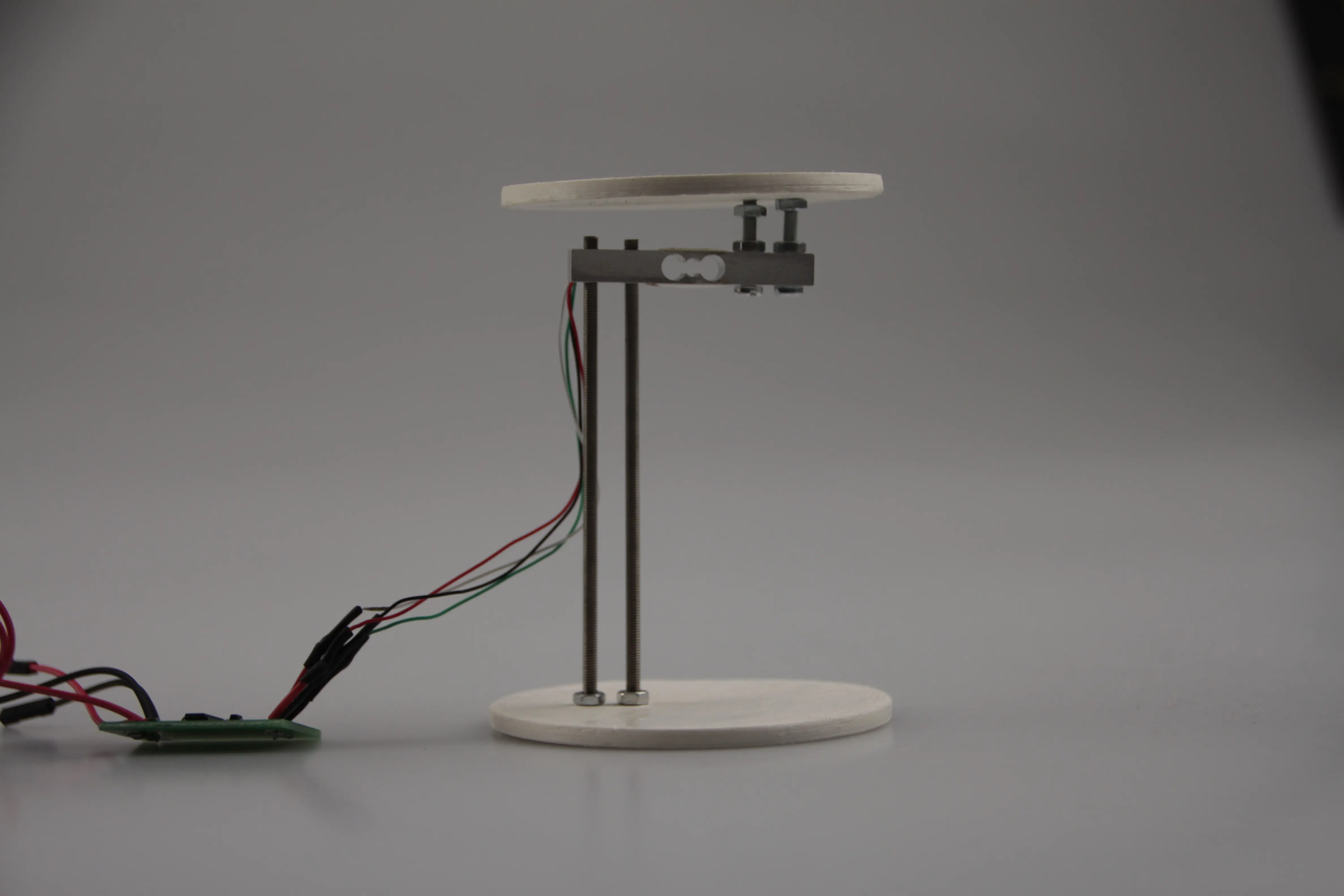 Load cell assembly with two 3D-printed discs and threaded rods, isolated on grey